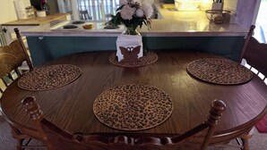 Ein Holztisch mit vier Stühlen, eine Blumenvase und eine Küchenarbeitsplatte im Hintergrund.