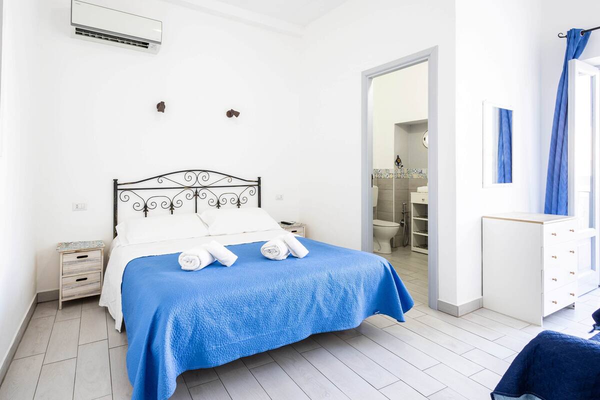 A neatly arranged bedroom with a bed, bedside table, and a wardrobe.