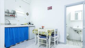 A compact kitchen with a blue curtain, a table with a patterned tablecloth, and a white sink.