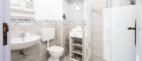 Un baño con inodoro, lavabo y cabina de ducha.