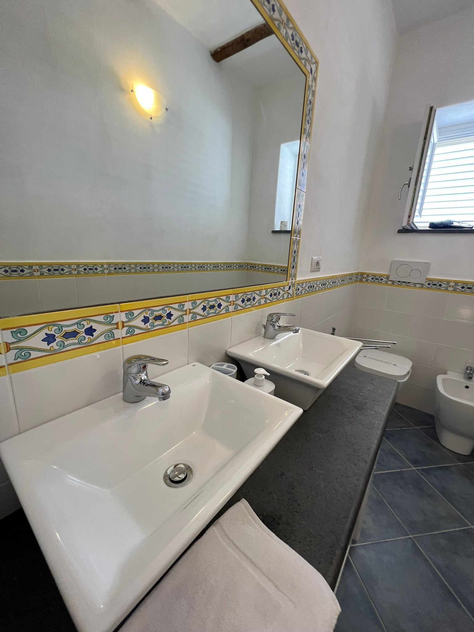 Une salle de bain avec deux lavabos, un bidet et un miroir.