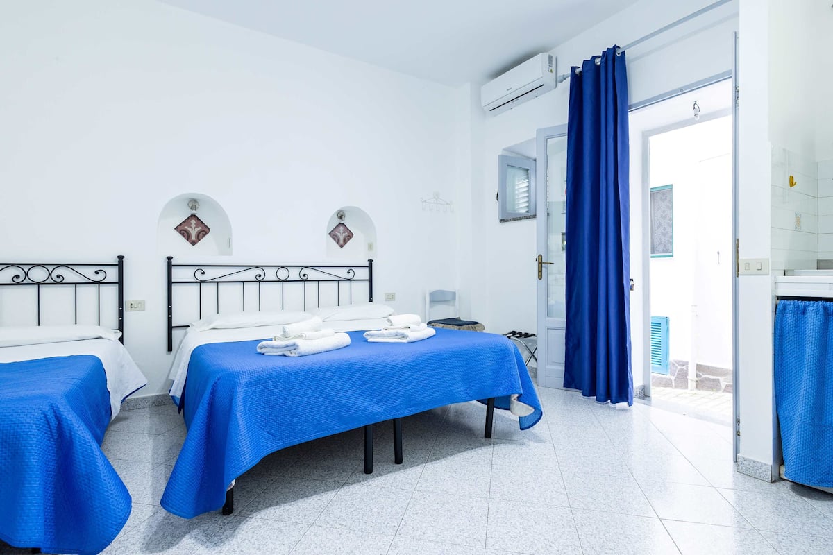 A hotel room with two beds, a bathroom, and a view of the outside.