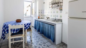 A compact kitchen with a window, a table with a checkered tablecloth, and a white refrigerator.