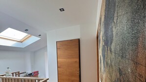 A modern interior with a wooden door, a skylight, and a large painting on the wall. - LePtiLoft Bayeux (Bayeux)
