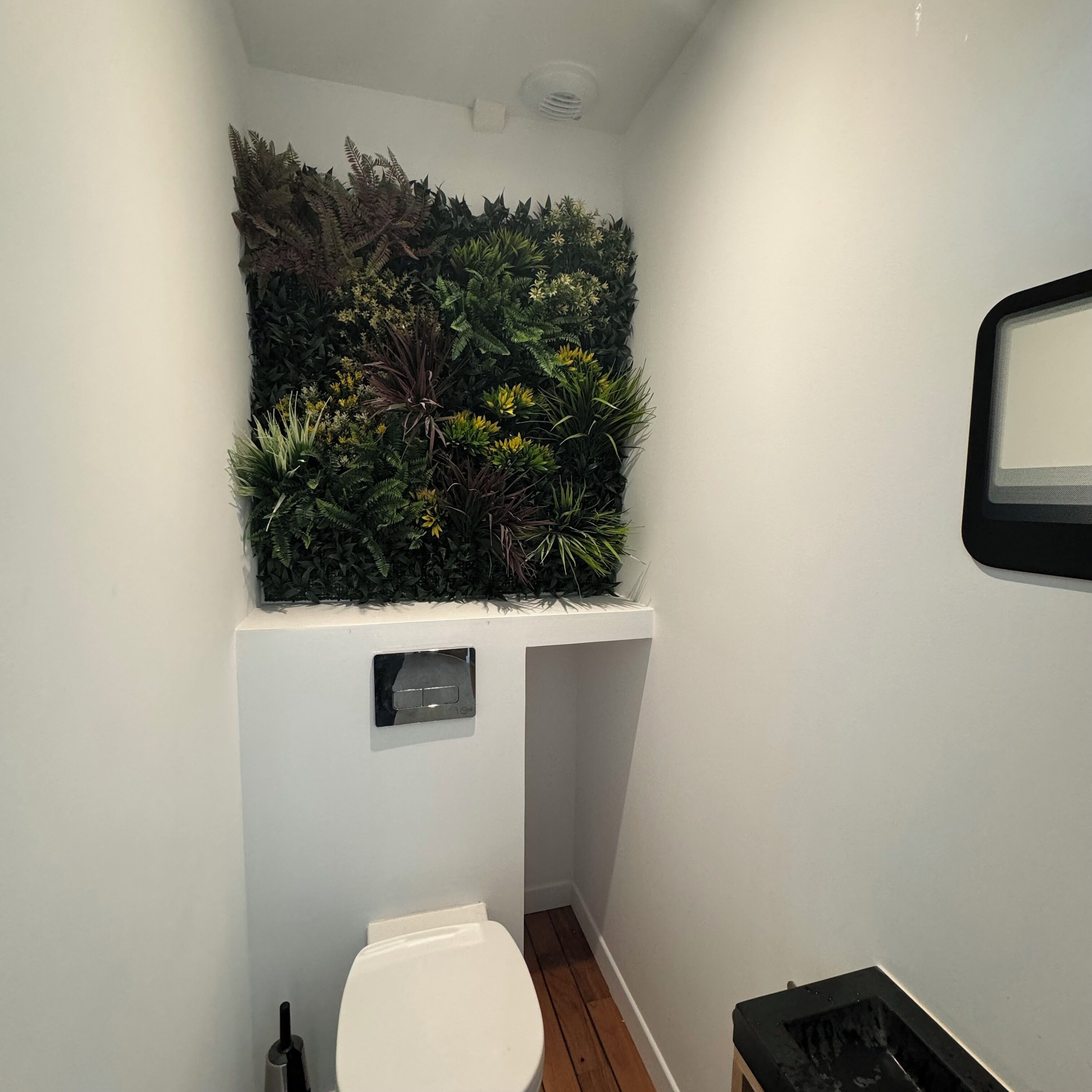 Een badkamer met een wit toilet, een klein wastafeltje en een spiegel bevestigd aan de muur.