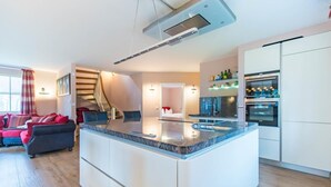 A modern kitchen with a central island, built-in appliances, and a staircase leading to an upper level. - Vacation home 4 seasons - island vacation in Glowe with heart and style from 4 persons (Glowe)