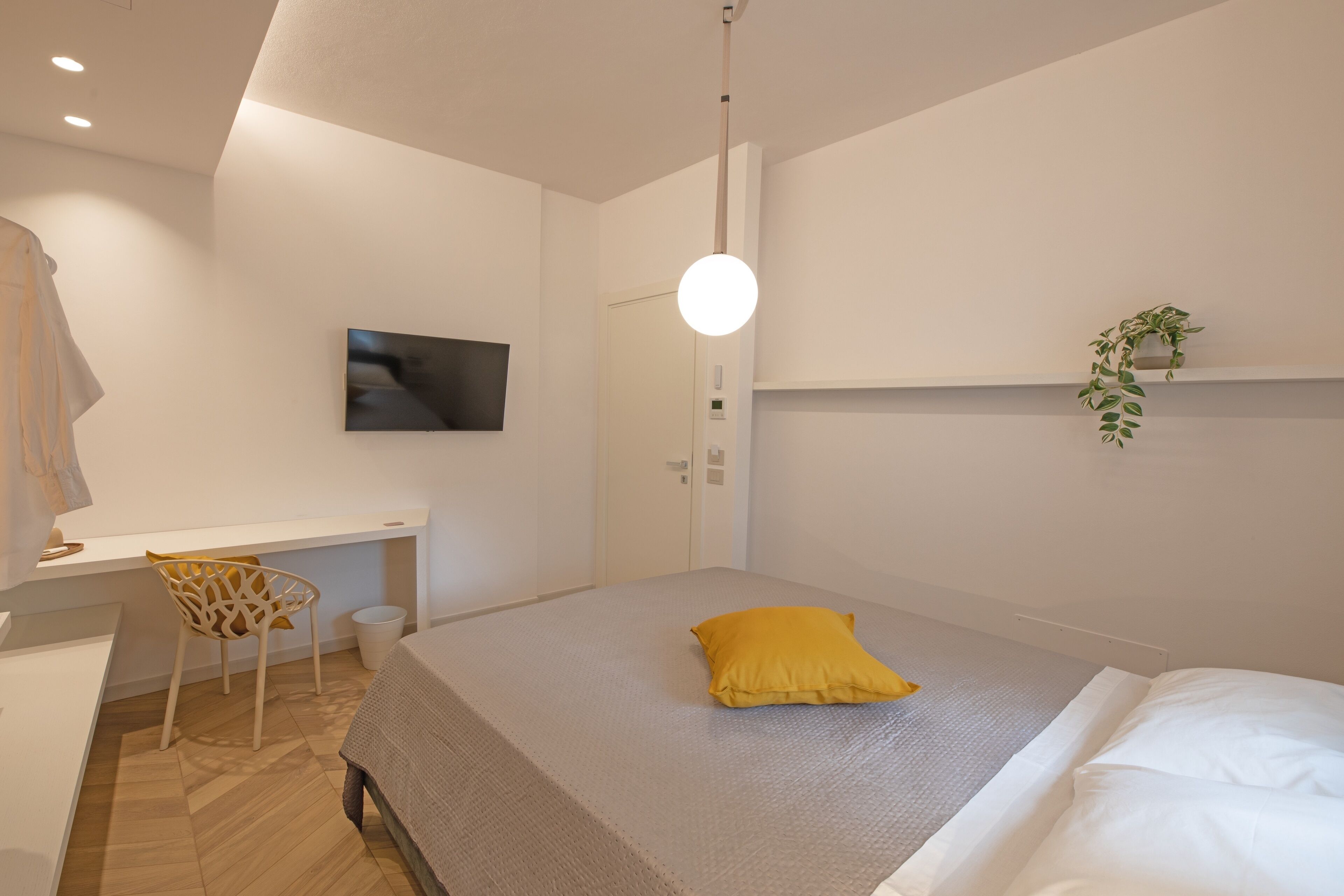 A modern bedroom with a bed, a desk, and a TV.
