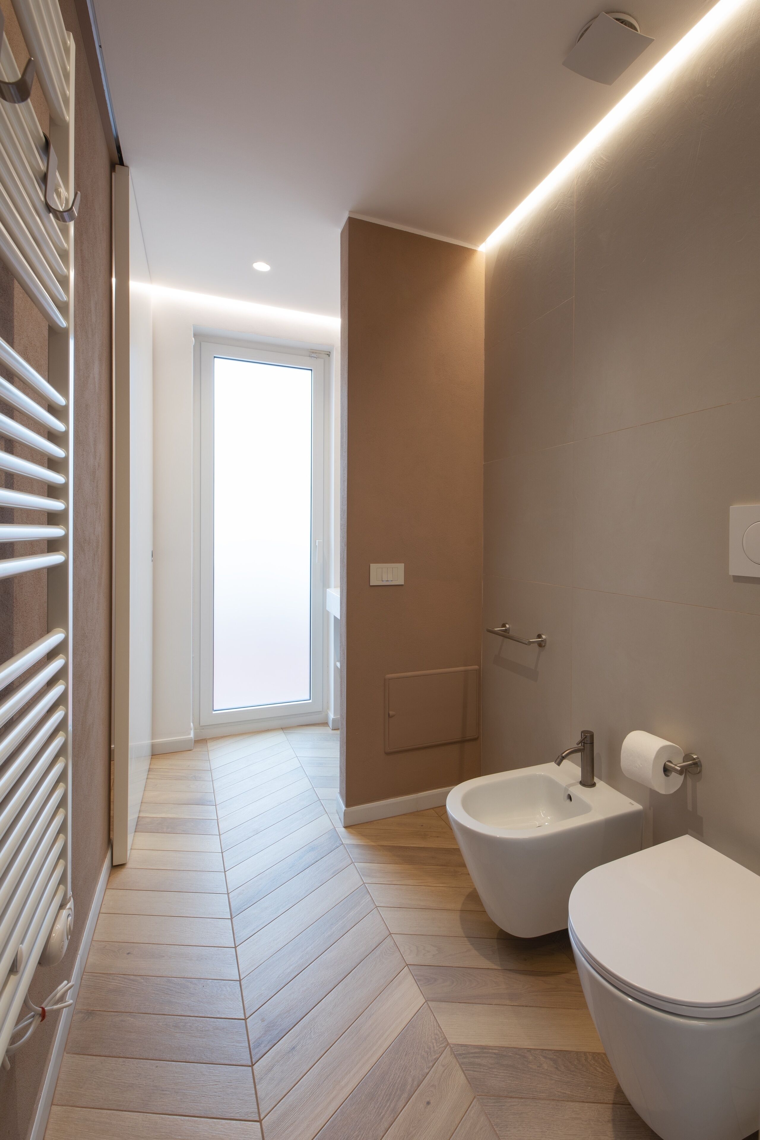 A modern bathroom with a bidet, toilet, and a walk-in shower.