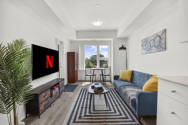 Relax in style. Enjoy the modern, light-filled living area featuring a cozy blue sofa, smart TV with Netflix, and stylish decor. The perfect spot to unwind after a day of exploring.