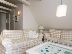 A room with two checkered sofas, a white table with decorative stones, a lamp, and a hanging light fixture.