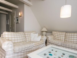 Una habitación con dos sofás estampados, una mesa blanca con piedras decorativas, una lámpara y un candelabro colgante.