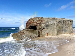 A large, weathered concrete structure by the beach with waves crashing against it. - 5 Star Holiday Home in Ulfborg (Ulfborg)