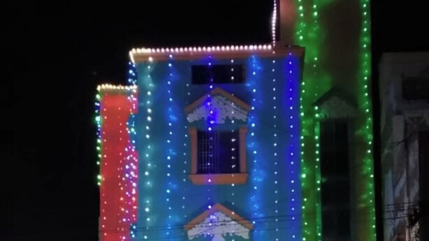 A building with a sign reading "Velan Lodge" and multiple windows, surrounded by colorful lights. - Velan Lodge (Neyveli)