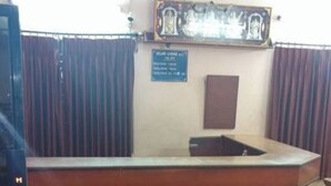 Un mostrador de recepción con detalles de madera, un letrero azul en la parte superior y un candelabro encima.