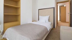 Una habitación de hotel con cama, un armario de madera y una puerta que da a otra estancia.
