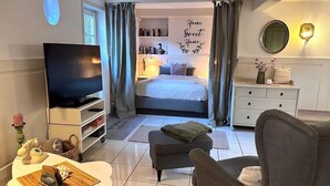 A compact hotel room with a bed, a television, a desk with a chair, and a small seating area. - Small break under thatch - quiet & cozy (Sankt Peter-Ording)