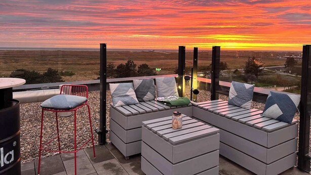 An outdoor seating area with a view of a sunset over a flat landscape. - Small break under thatch - quiet & cozy (Sankt Peter-Ording)