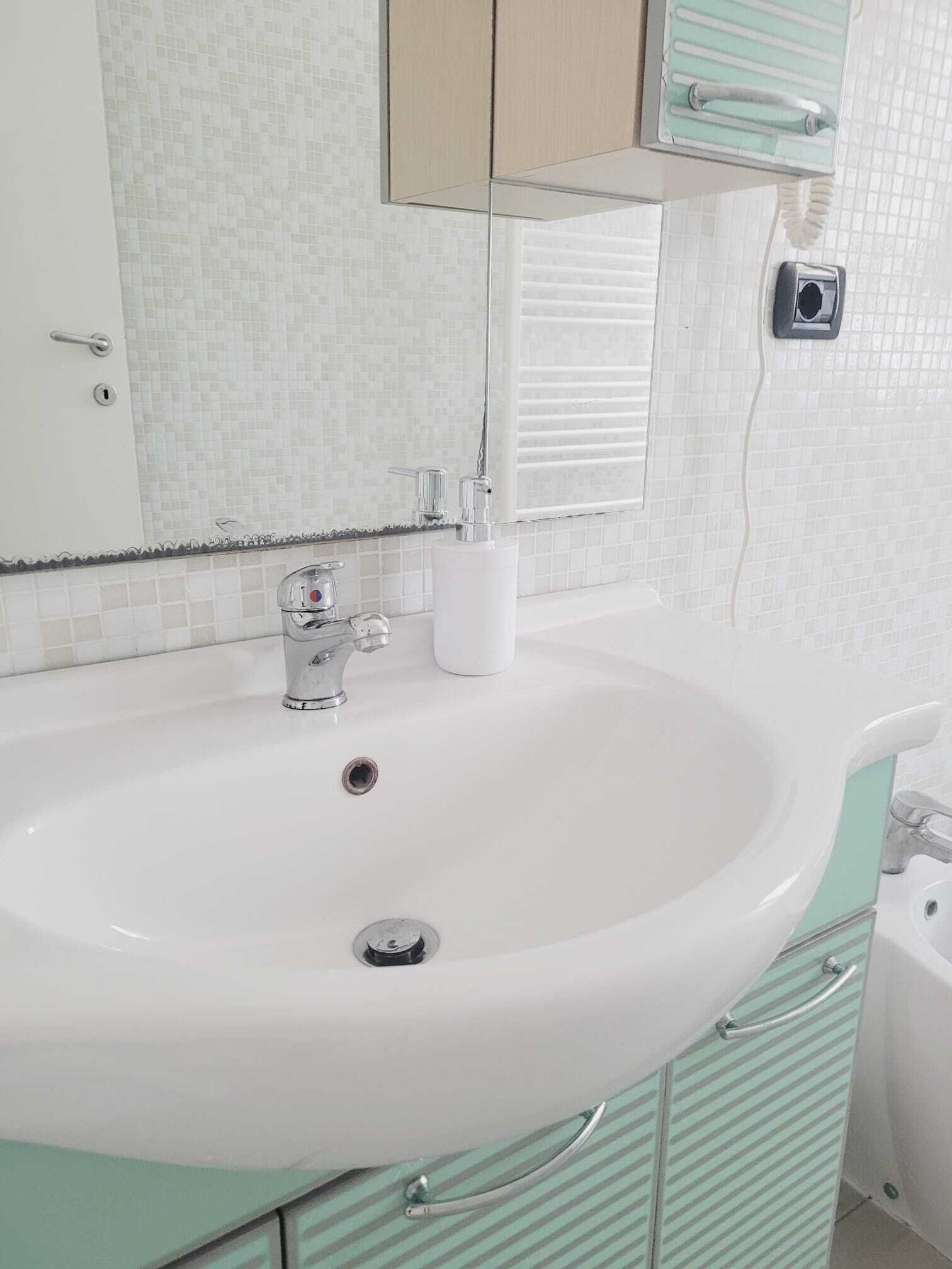 A bathroom with a white sink, a mirror, and a toilet.