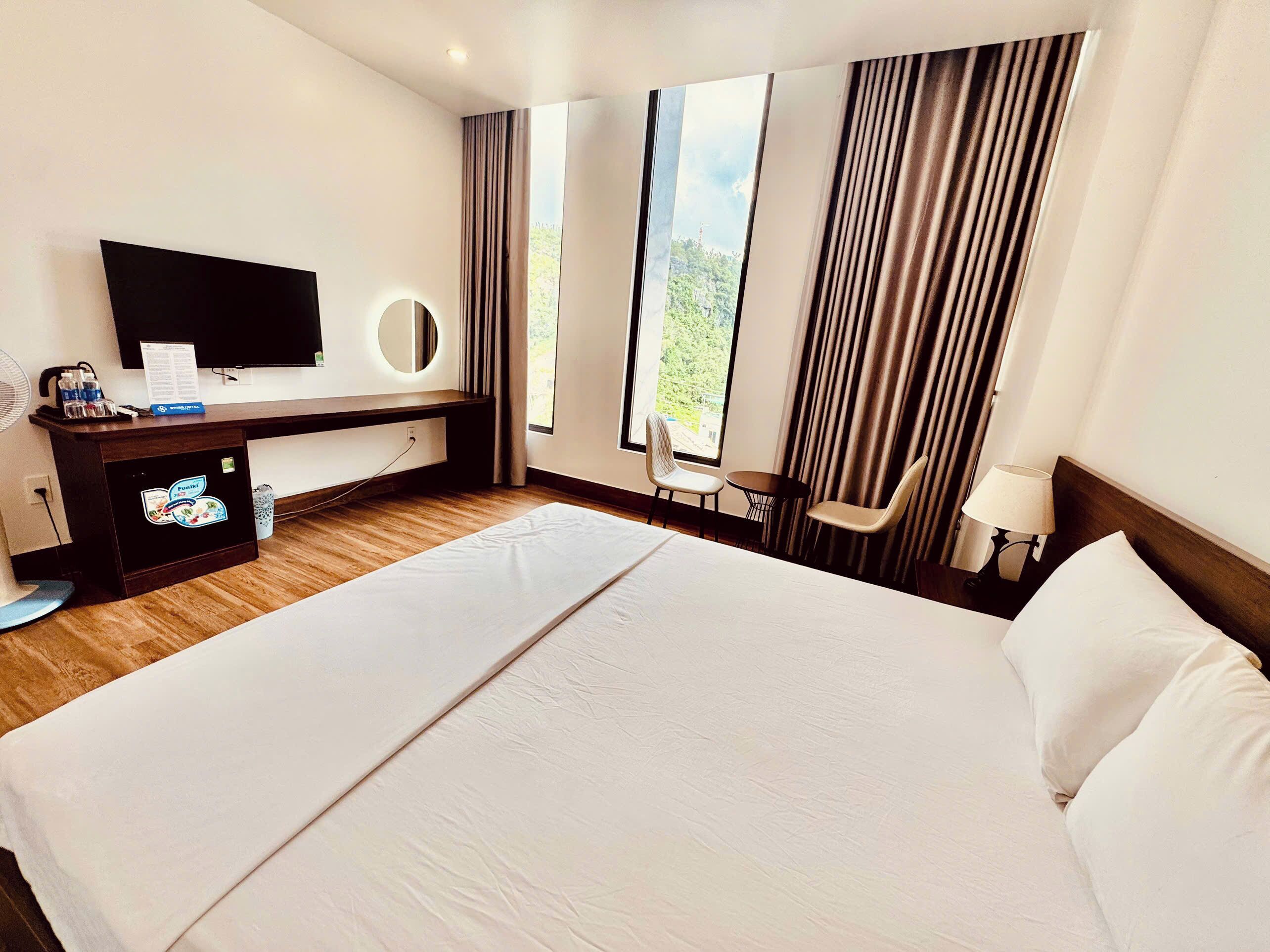Une chambre d’hôtel avec un grand lit, un bureau doté d’un téléviseur à écran plat, une petite table et deux chaises.