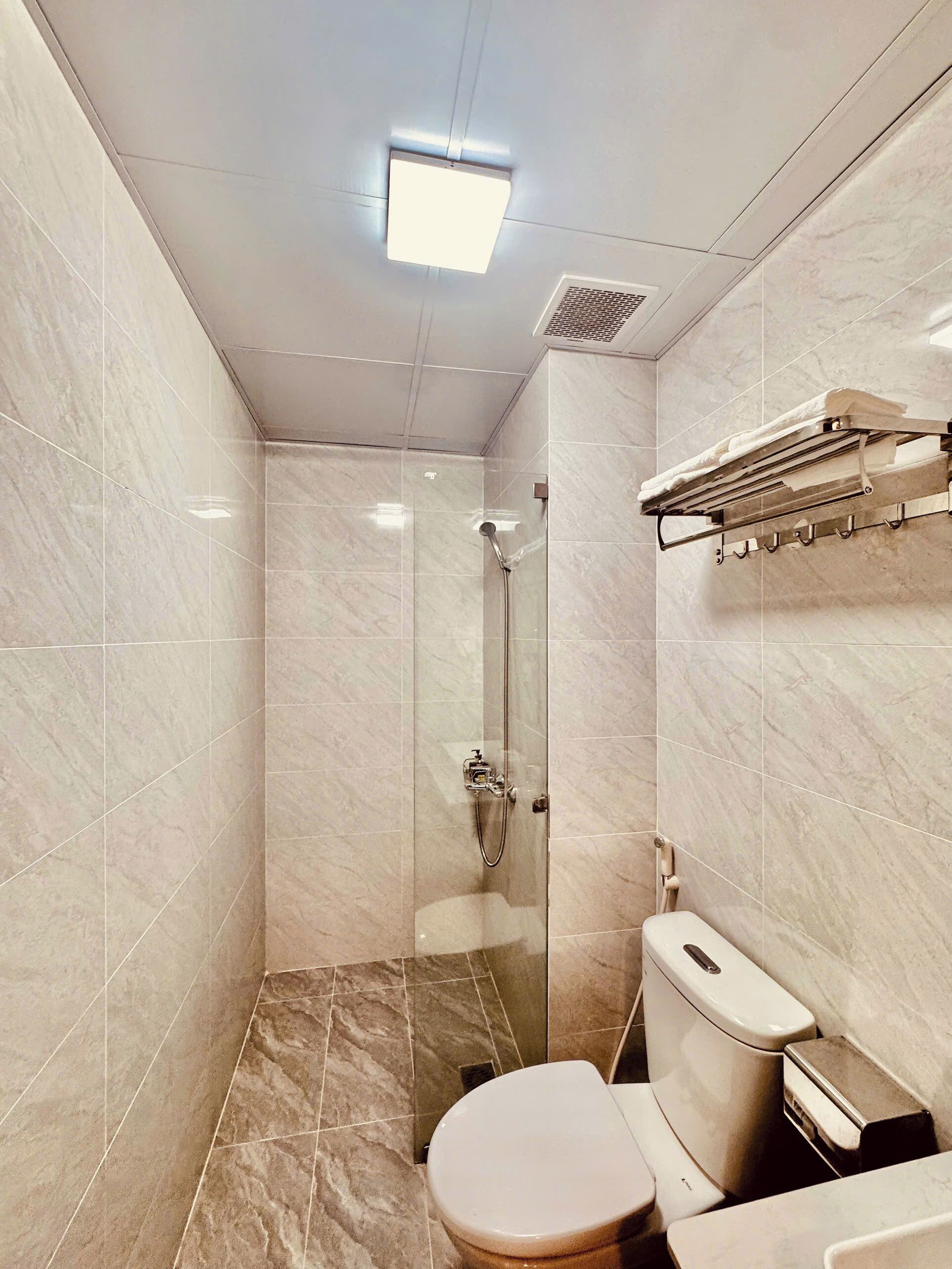 A modern bathroom with a glass-enclosed shower, a toilet, and a towel rack.