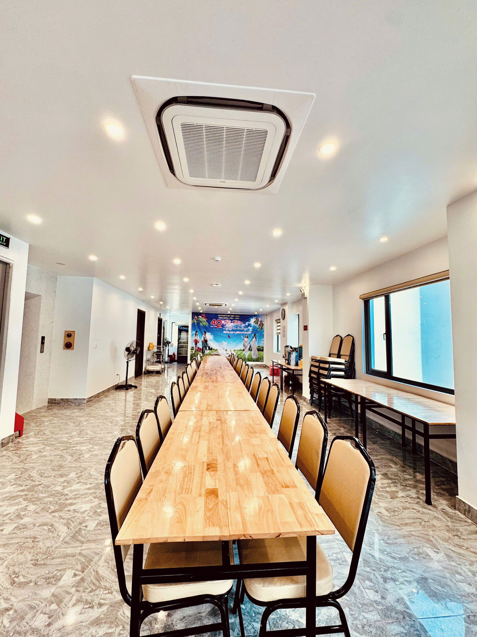 A conference room with a long wooden table, chairs, a ceiling fan, and a large window.
