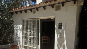 Un petit bâtiment blanc, avec un toit en tuiles et un portail en métal. Une plaque sur le mur indique : « N° 24, l’appartement ».