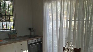 A kitchen with a stove, oven, and window with curtains. - Gorgeous One Bedroom Apartment in Peaceful Jesus Hills, Ibiza (Can Bessó)