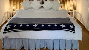 Un lit avec une housse de lit à rayures, deux lampes de chevet et un mur recouvert de lambris en bois verticaux.