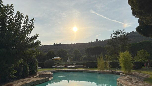 A swimming pool with a stone border, surrounded by greenery and trees. - Condo Cortona, luxury apartment for 4 with pool and garden in Tuscany! (Cortona)