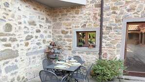 A stone building with a small outdoor dining area featuring a table and chairs. - Condo Cortona, luxury apartment for 4 with pool and garden in Tuscany! (Cortona)