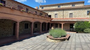 A courtyard with stone buildings, arched walkways, and potted plants. - Condo Cortona, luxury apartment for 4 with pool and garden in Tuscany! (Cortona)