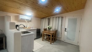 A compact kitchen with a sink, a refrigerator, a dining table with chairs, and a door with a window. - Charming Studio in lovely El Prado with AC (El Prado)
