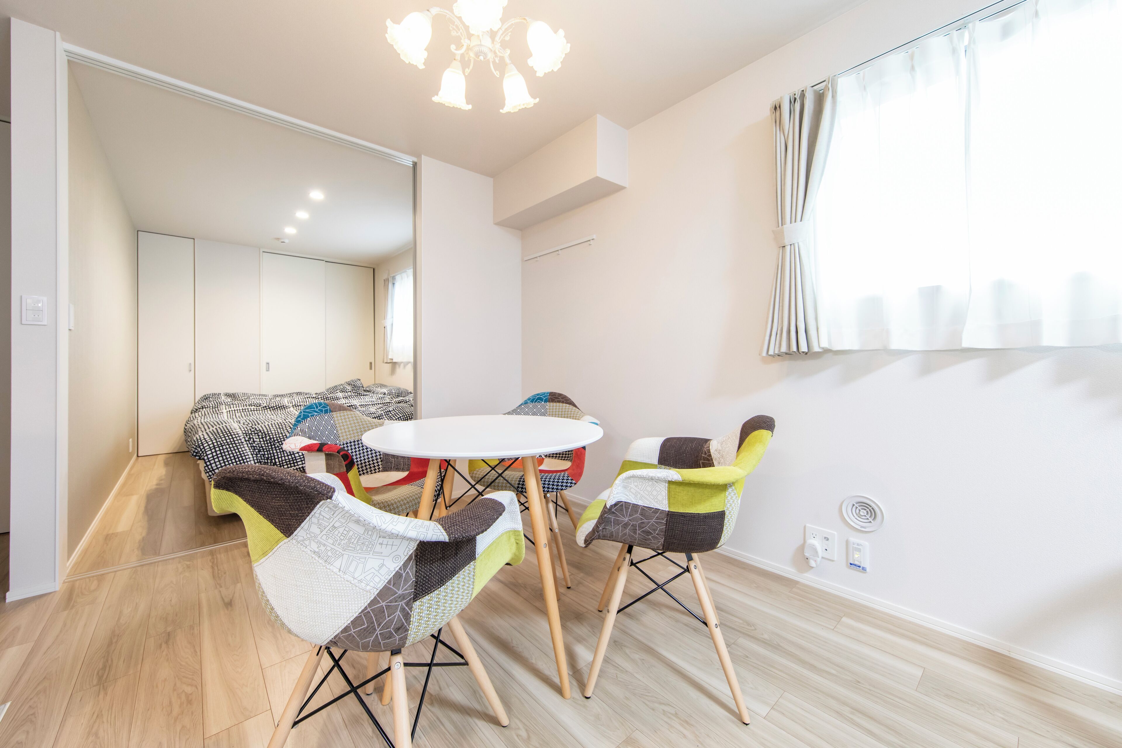 Una habitación moderna con una mesa redonda, dos sillas, una cama con ropa de cama estampada y un espejo grande.