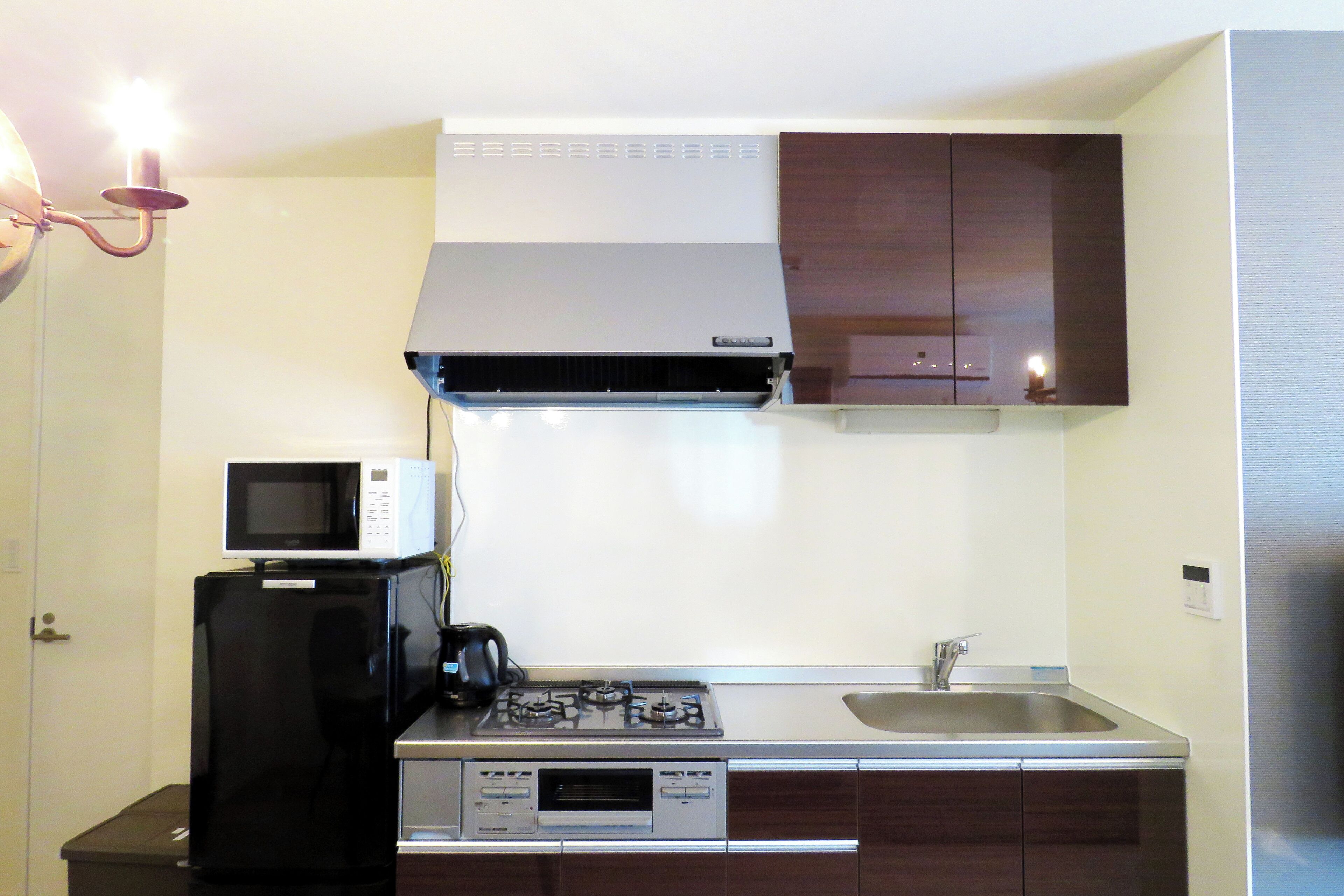 Una cucina compatta con forno a microonde, fornello e lavello.
