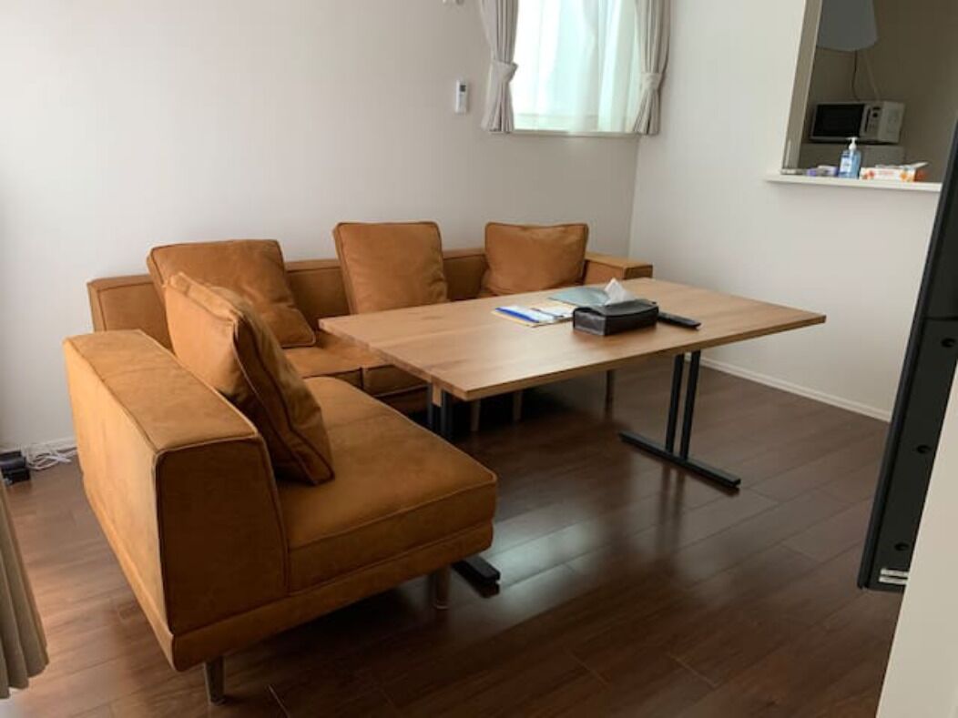 A modern living room with a sofa set, a wooden coffee table, and a flat-screen TV on a stand.