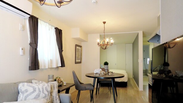 A modern living room with a sofa, chairs, a dining table, and a chandelier. - MAISON DE AILE (Takasaki)
