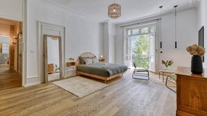 A bedroom with a wooden bed, a large window, and a view of greenery outside. - Facing the Mont Blanc range. (Chamonix-Mont-Blanc)