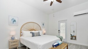 A modern bedroom with a large bed, bedside tables, a bench, and a ceiling fan.