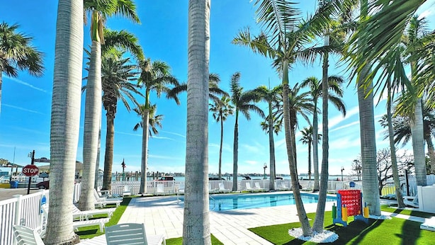 A poolside area with palm trees, lounge chairs, and a pool.
