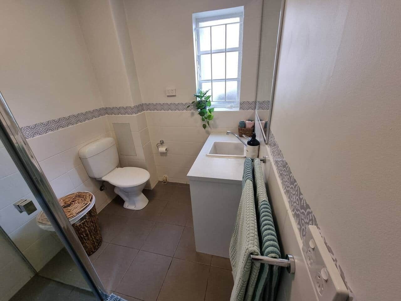 A small bathroom with a toilet, sink, and window.