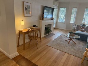 Un salon avec une cheminée, un téléviseur, un coin repas comprenant une table et des chaises, et un canapé.