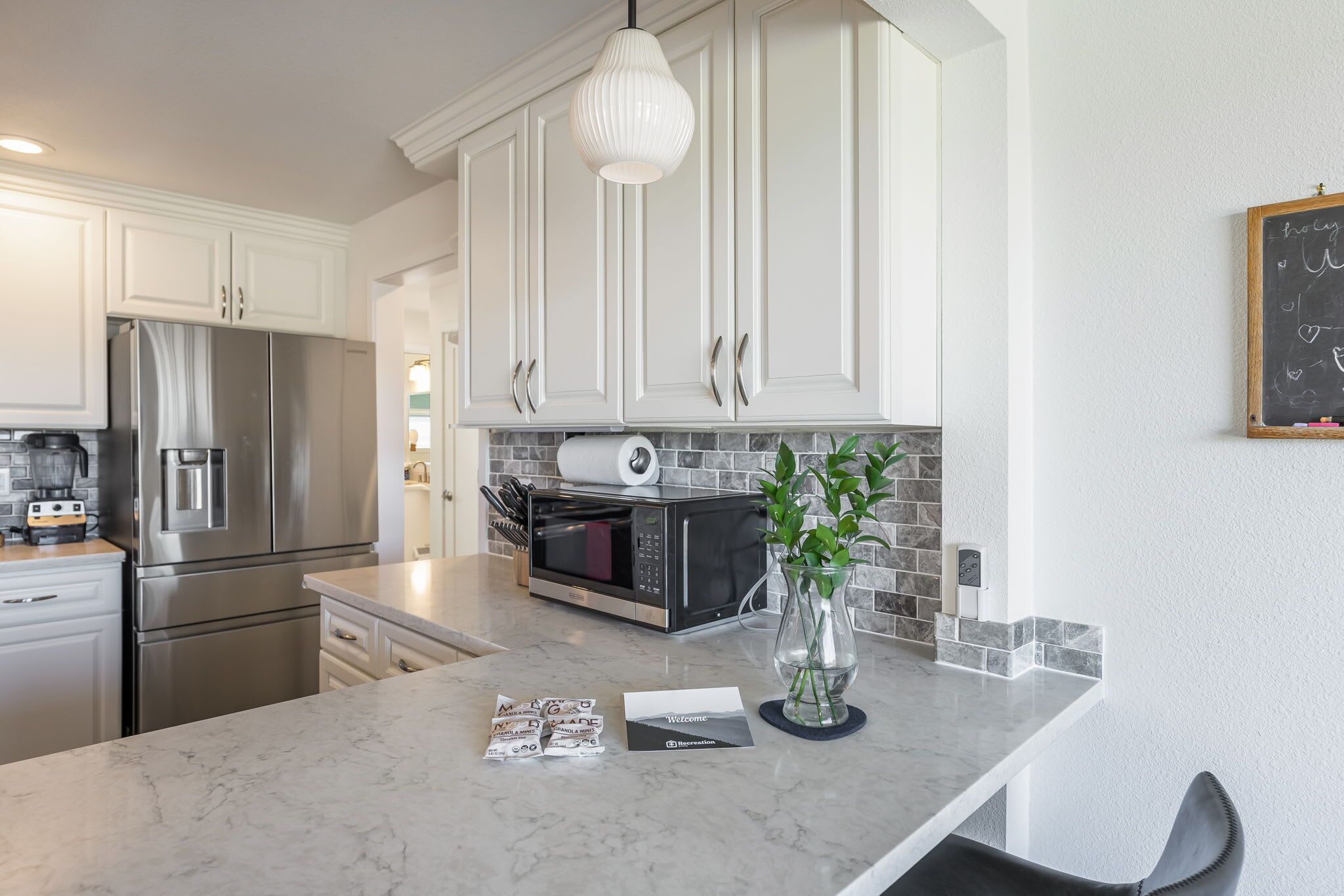 Una cocina moderna con armarios blancos, electrodomésticos de acero inoxidable y encimera de mármol.