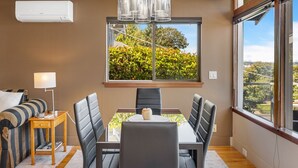 A modern dining area with a table, chairs, and a window with a view of greenery. - Queen Anne | Views | Near Shopping & Dining (Seattle)