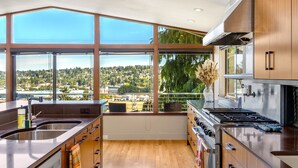 A modern kitchen with large windows, a stove, and a sink. - Queen Anne | Views | Near Shopping & Dining (Seattle)