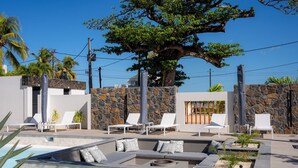 A pool area with lounge chairs and a stone wall. - CasaWapa - Waterfront Apartment (Pointe d'Esny)
