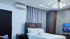 Ett modernt hotellrum med en stor säng, en platt-TV, ett soffbord i glas och en soffa.