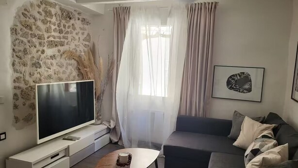 Una sala de estar con pared de piedra, un televisor de pantalla plana, un sofá y una mesa de centro.