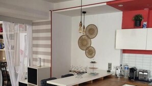 Una cocina compacta con una isla central, muebles blancos y una pared de acento roja.