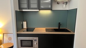 Una cocina compacta con microondas integrado, un lavamanos y una encimera de madera.