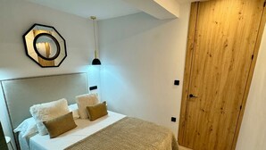 Une chambre à coucher avec un lit, une porte en bois et un miroir fixé au mur.